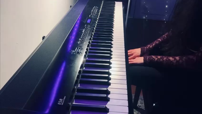 Mains jouant sur un piano numérique éclairé de violet, pour l’extrait du Prélude de Chopin.